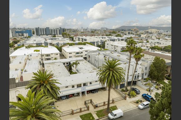 arial view of a large white building with white roofs and palm trees in front of it